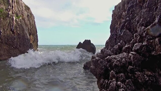 Strong waves in the cove between the rocks of the cliff.