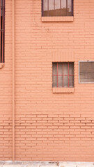 Rejilla de ventilación y ventanas en pared rosa de callejón urbano