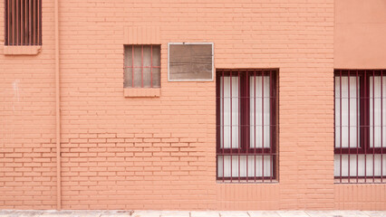 Rejilla de ventilación y ventanas en pared rosa de callejón urbano