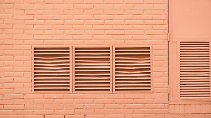 Rejilla de ventilación y ventanas en pared rosa de callejón urbano