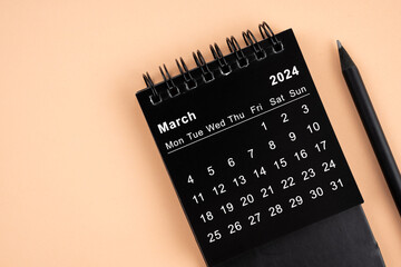 March 2024 Black spiral desktop calendar and wooden pencil.
