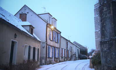 Charming country road winding through historic houses and towering buildings in Saint-Loup-de-Naud
