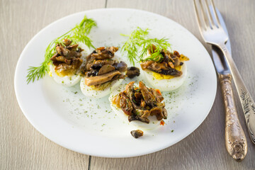 boiled eggs stuffed with mushrooms and spices in a plate .