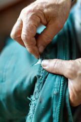 Old Man Hands Repairing by Sewing a Jacket Hole Close Up