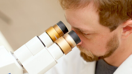 A medical scientist conducts experiments with DNA under a microscope in a biological laboratory....