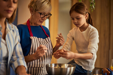 Three generations in the kitchen, little helping her grandma and mother.