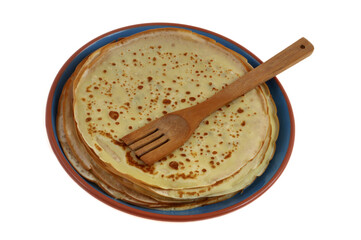 Fourchette en bois posée sur une pile de crêpes dans une assiette en gros plan sur fond blanc