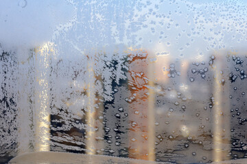 Frosty patterns on window glass, defocused view to residential buildings in winter