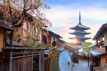 Scenic cityscape of Yasaka pagoda sunset in Kyoto with a young Japanese woman in a traditional...