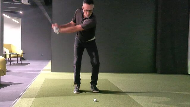 Male golfer plays golf indoors on golf simulator closeup. Driving range with screen