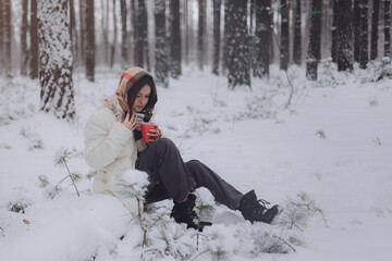 Portrait of a young pretty girl in a winter snowy forest. Happy girl in winter scenery, holding a...