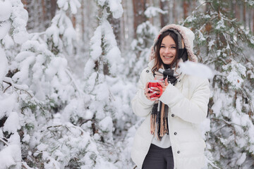 Portrait of a young pretty girl in a winter snowy forest. Happy girl in winter scenery, holding a...