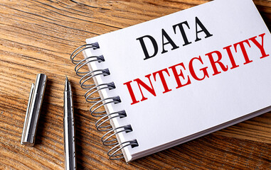 DATA INTEGRITY text on notebook with pen on wooden background