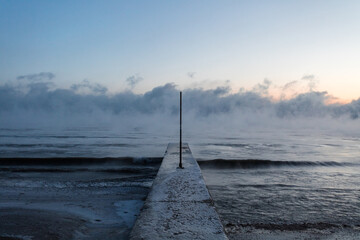 Ice covered concrete pier leading out to fog covered Lake Michigan on bitterly cold and freezing day - 710640357