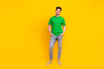 Fototapeta na wymiar Full size photo of handsome guy wear stylish t-shirt arms in pockets look at discount empty space isolated on yellow color background