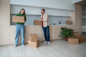 Joyful couple embraces start as move into new home, holding boxes with belongings, radiate...