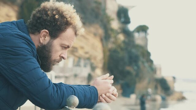 Deep Autumn Sadness: Young Man Leaning on Seafront Railing