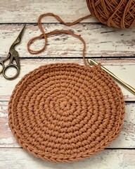 Unfinished crochet round shape placemat on a wooden surface