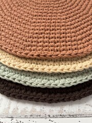 Colourful round shaped hand-knitted placemats on a wooden surface