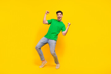 Fototapeta na wymiar Full length photo of ecstatic funny man dressed green t-shirt jeans raising fists scream yeah win bet isolated on yellow color background