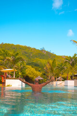 happy man swims in a pool in the Seychelles, the concept of a summer vacation