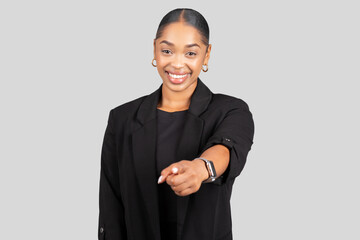 Engaging young woman in a tailored black blazer extends her arm confidently towards the camera