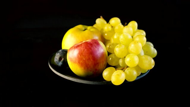 Ripe sweet juicy apples and a large bunch of ripe grapes on a black background. Ideal for content about a healthy lifestyle and healthy food. Vegan products.