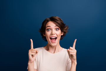 Portrait of amazed lady worker showing empty space discount banner open mouth isolated on dark blue color background