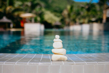 pyramid of stones by pool, balanced zen stones, spa and relax concept