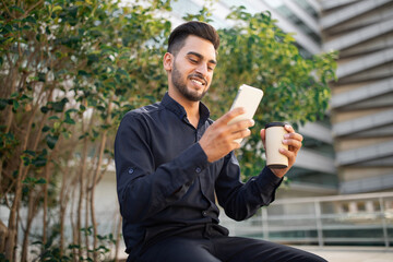 Fototapeta premium arabic businessman talking on smartphone video calling drinking coffee outside