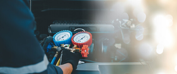 Close up hand of auto mechanic using measuring manifold gauge check the refrigerant and filling car...