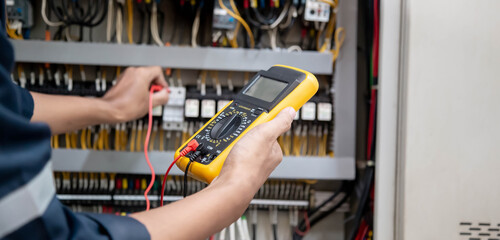 Engineer testing electrical system Using a multimeter to measure the current at the control cabinet.