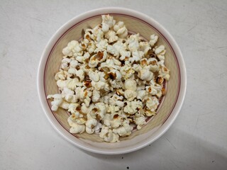Popcorn in a bowl on a white background, top view.