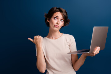 Photo of lovely lady hold netbook point look skeptical empty space dressed stylish white garment...