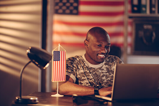 Young American soldier working on laptop at army base