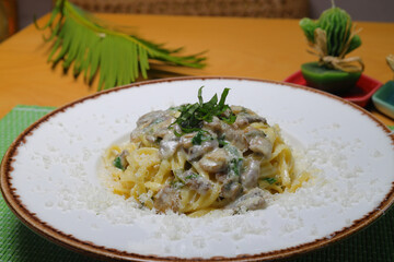 Detail of a plate full of tagliatelle with wild mushrooms and sausage.