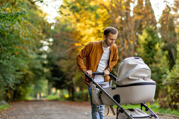 happy father pushing infant baby stroller and walking in the park. Spending time with newborn and breathing fresh air. - obrazy, fototapety, plakaty