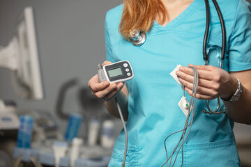 Doctor showing ECG holter monitor to patient in pediatric clinic. Holter monitoring device in a...