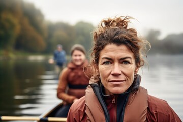 shot of an experienced female rower standing on a boat with her teammates in the background