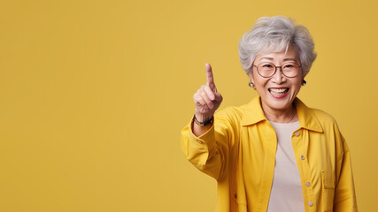Happy senior asian woman point her finger at copy space for promotion
