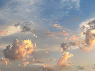 A vibrant sunset casts a warm orange glow on unique cloud formations, creating a striking contrast...