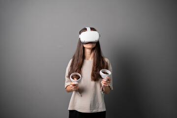 A woman, equipped with virtual reality glasses and controllers, actively plays games in an indoor...