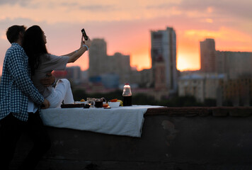 man and woman enjoying the serene beauty of a sunset from a rooftop ledge.