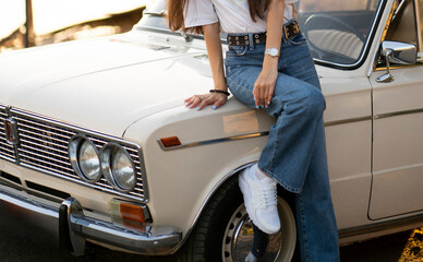 This image captures a womans lower legs as she is wearing trendy white sneakers paired with classic blue jeans on an urban sidewalk.