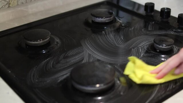 a woman cleans a gas stove in the kitchen. housewife doing housework in the kitchen