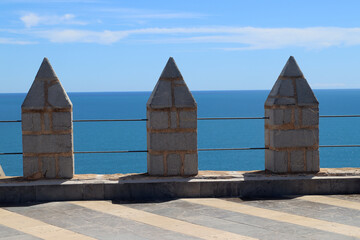 Metal railing with stone posts against blue sea and sky