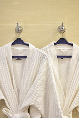 Close up of white bathrobes hanging on classic stone wall
