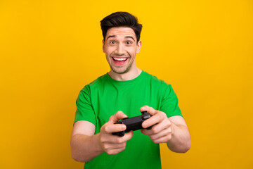 Photo portrait of handsome young brunet guy play station promo dressed stylish green outfit isolated on yellow color background