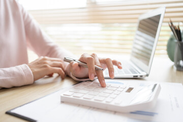 Close-up of hand pressing calculator to calculate income tax and company income in private office,...