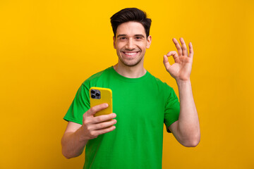 Photo of cheerful happy man wear green t shirt demonstrate nice feedback okey sign ad apple iphone...